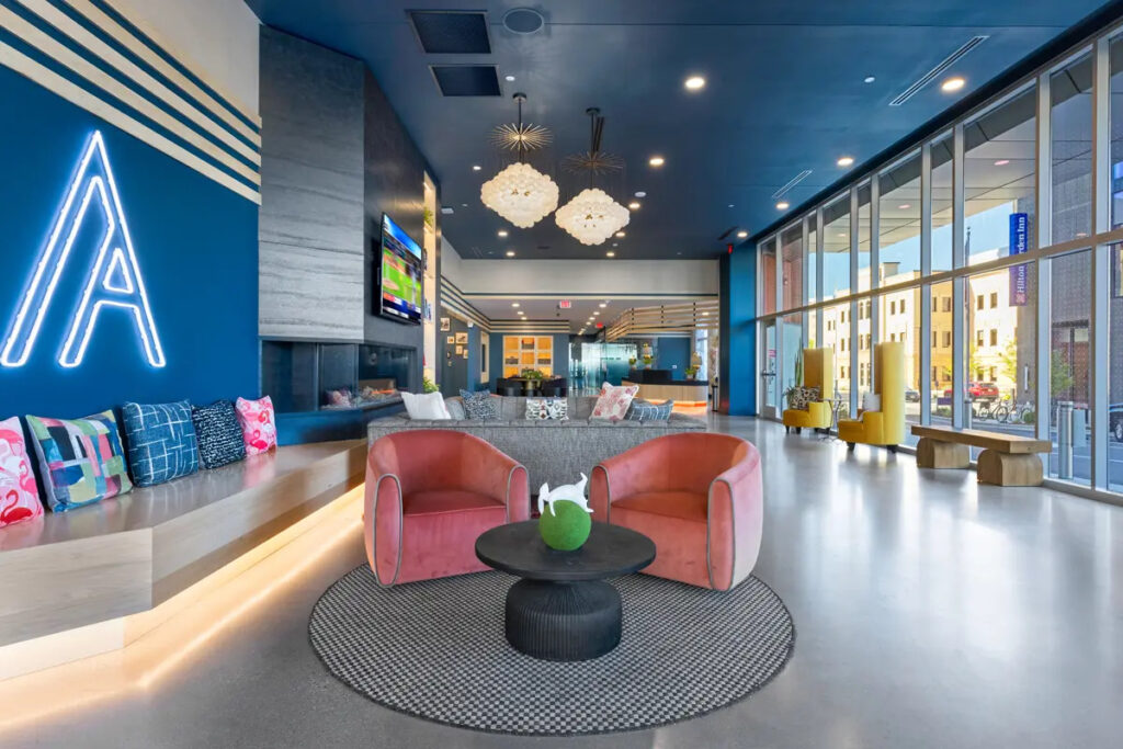 Colorful lounge area with neon sign, bright chairs, and artful lighting