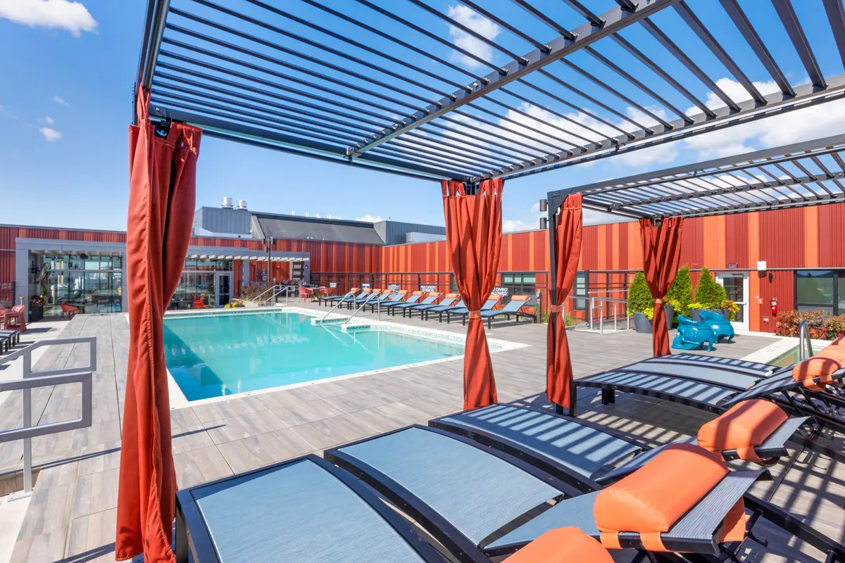 Poolside cabanas with orange curtains and modern seating