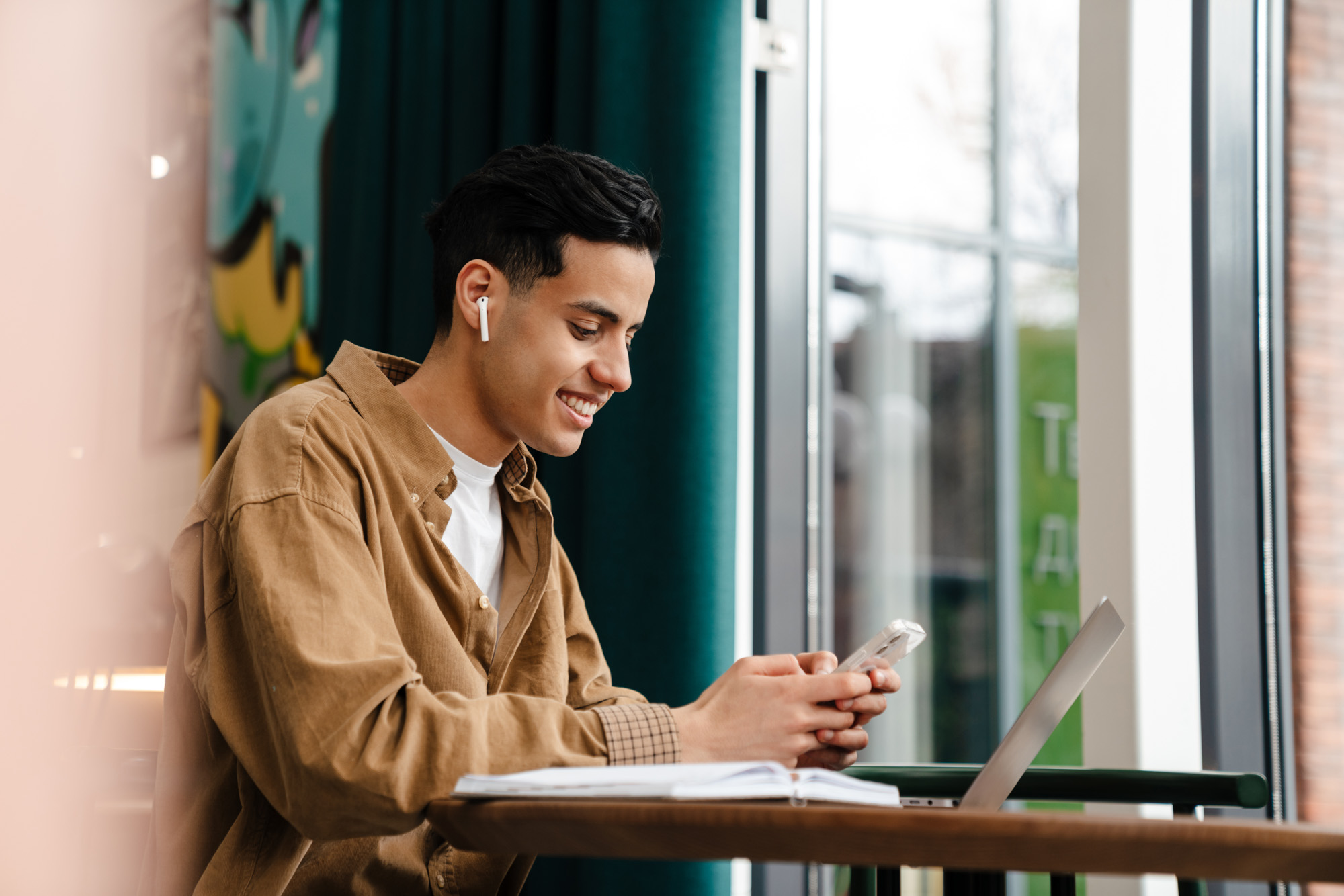 Young hispanic man student sitting at the cafe table indoors