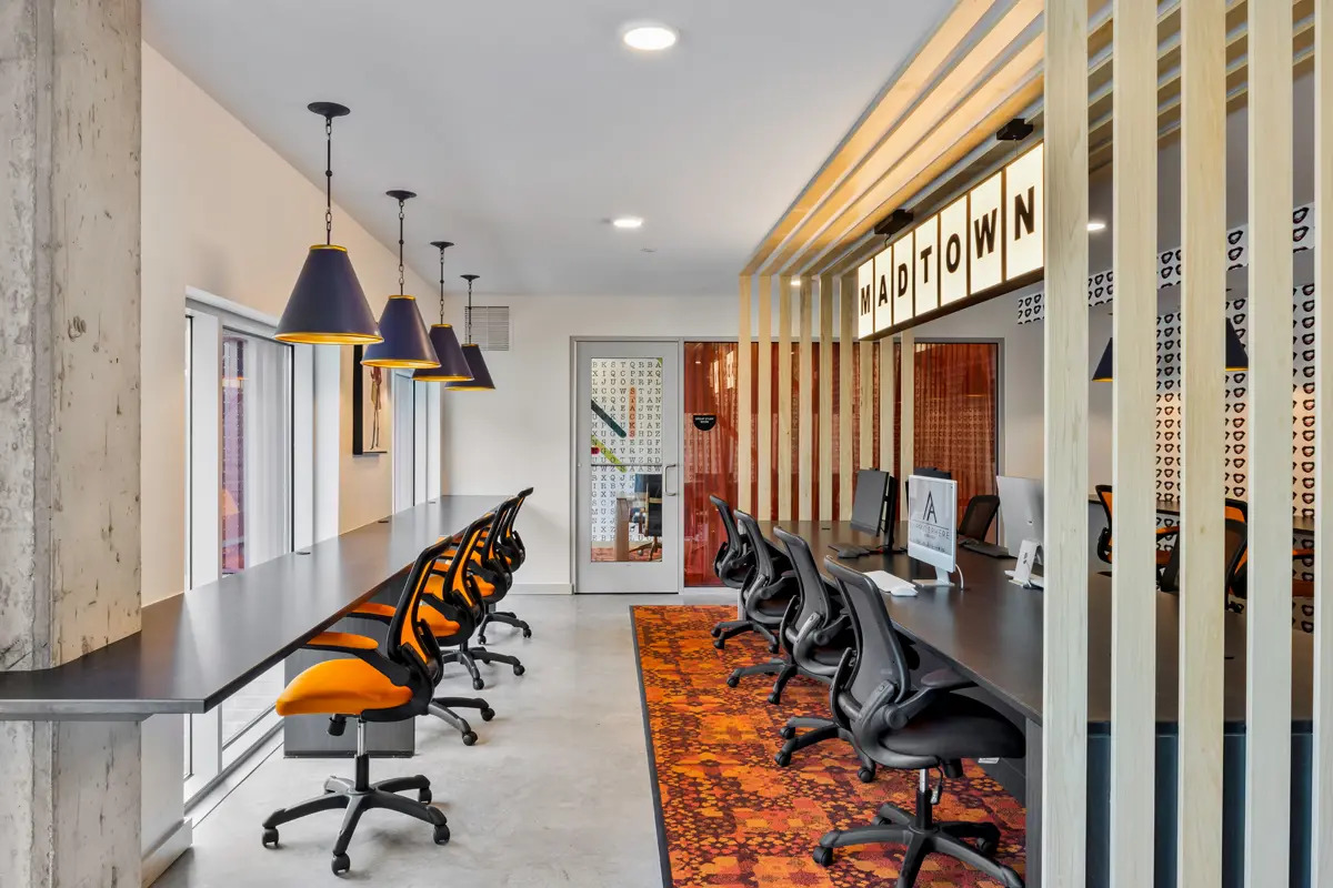 Study area with vibrant orange carpet, office chairs, and artful lighting that says Midtown